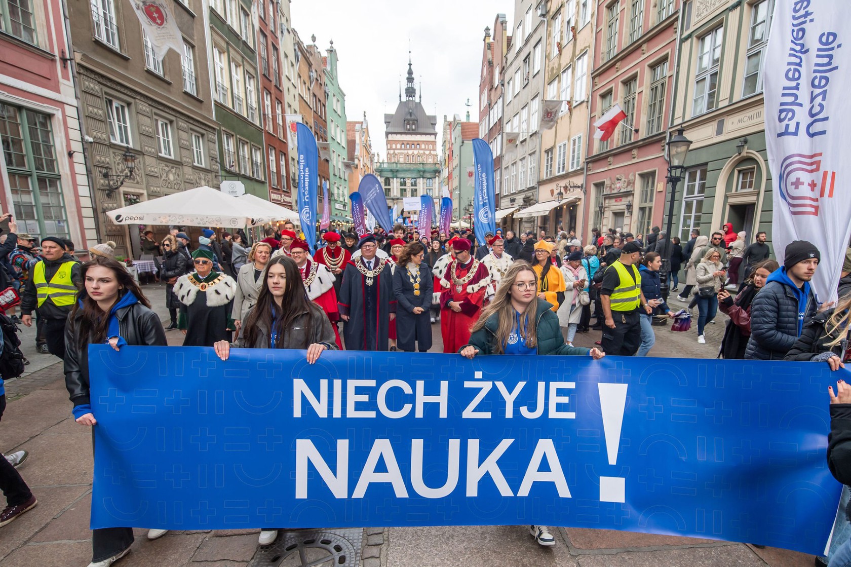 Ulica Długa w Gdańsku, na niej studenci i rektorzy gdańskich uczelni podczas inaugurującej parady. Cztery osoby niosą napis: Niech żyje nauka!