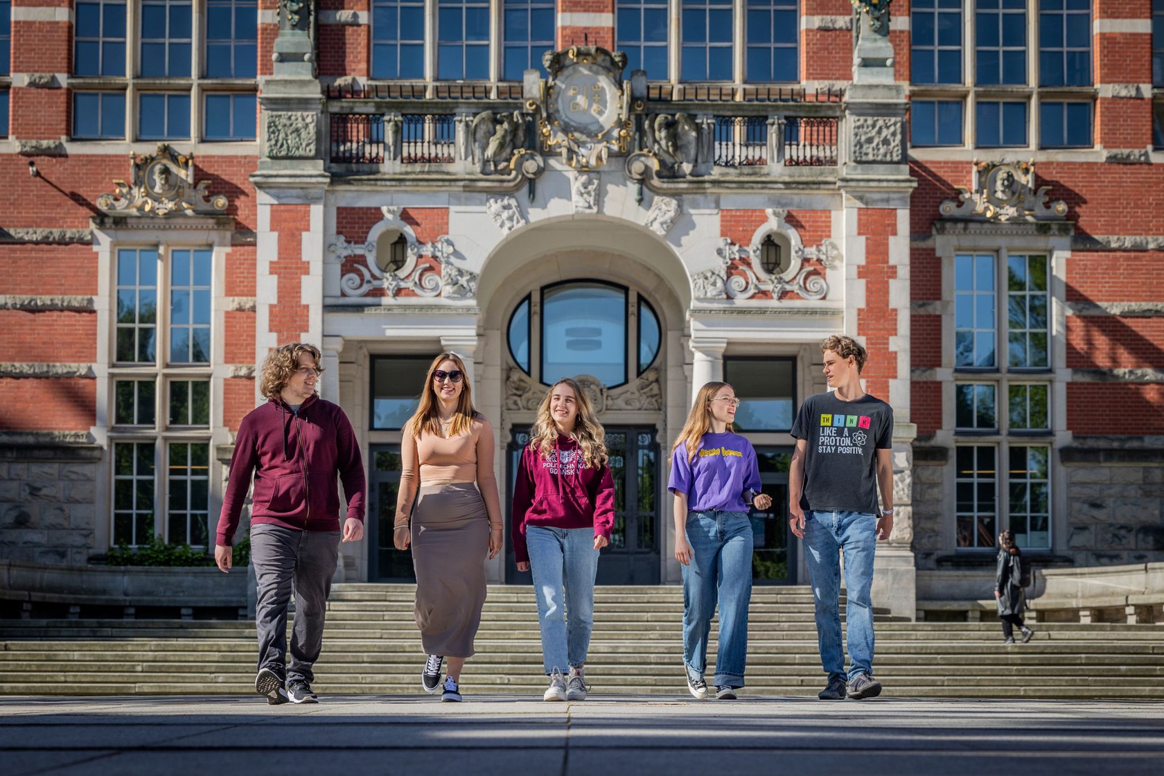 Pięcioro studentów kolorowo ubranych, przed schodami Gmachu Głównego Politechniki Gdańskiej. Trzy dziewczyny, dwoch chłopaków.