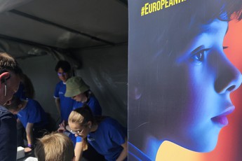 osoby pod namiotem pokazowym, po lewej roll-up z reklamą