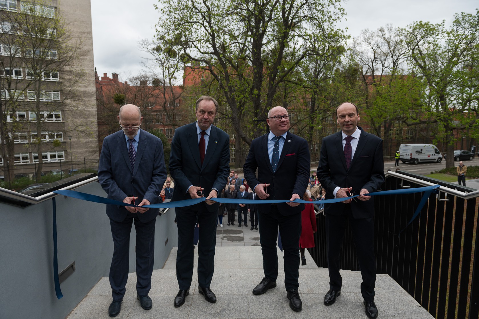 Czterech mężczyzn przecina wstęgę.