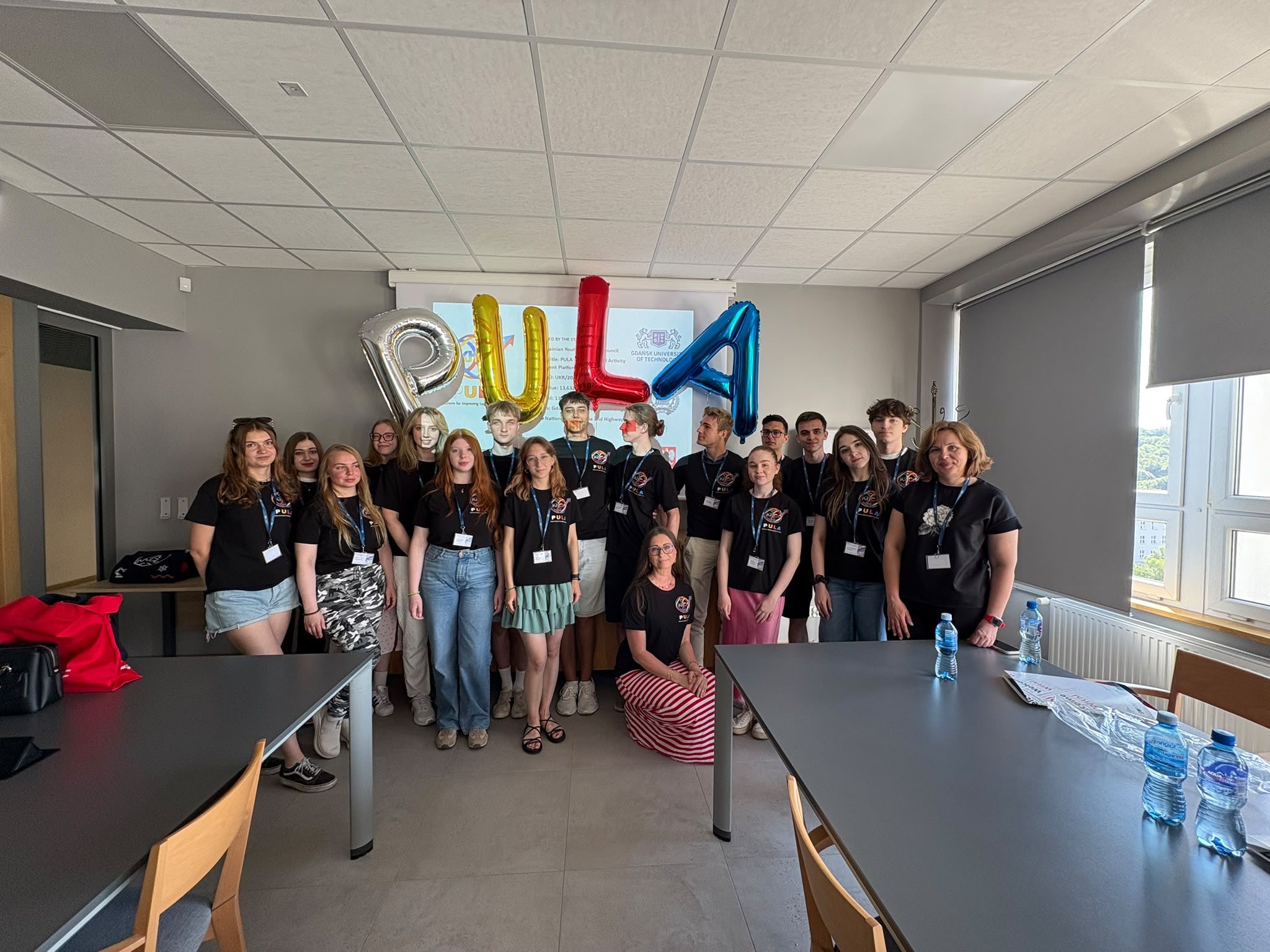 Photo of the project participants in the conference room under the PULA sign made of balloons