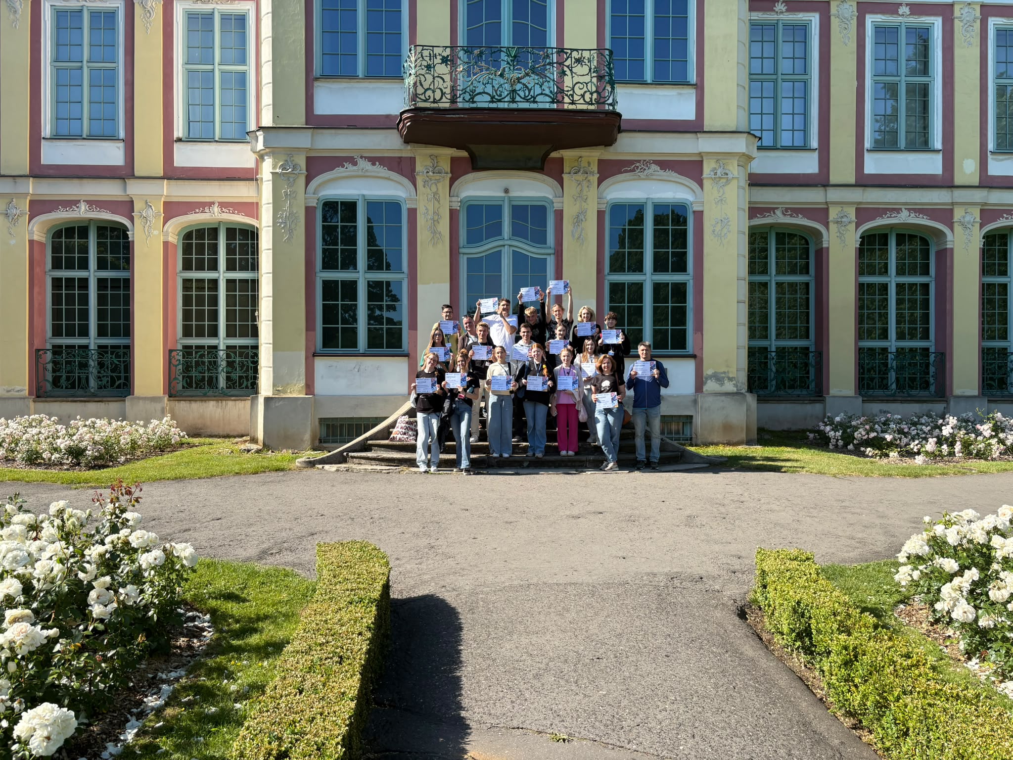 Photo of program participants on the steps of the manor house in Oliwa Park holding certificates of participation in the PULA project.