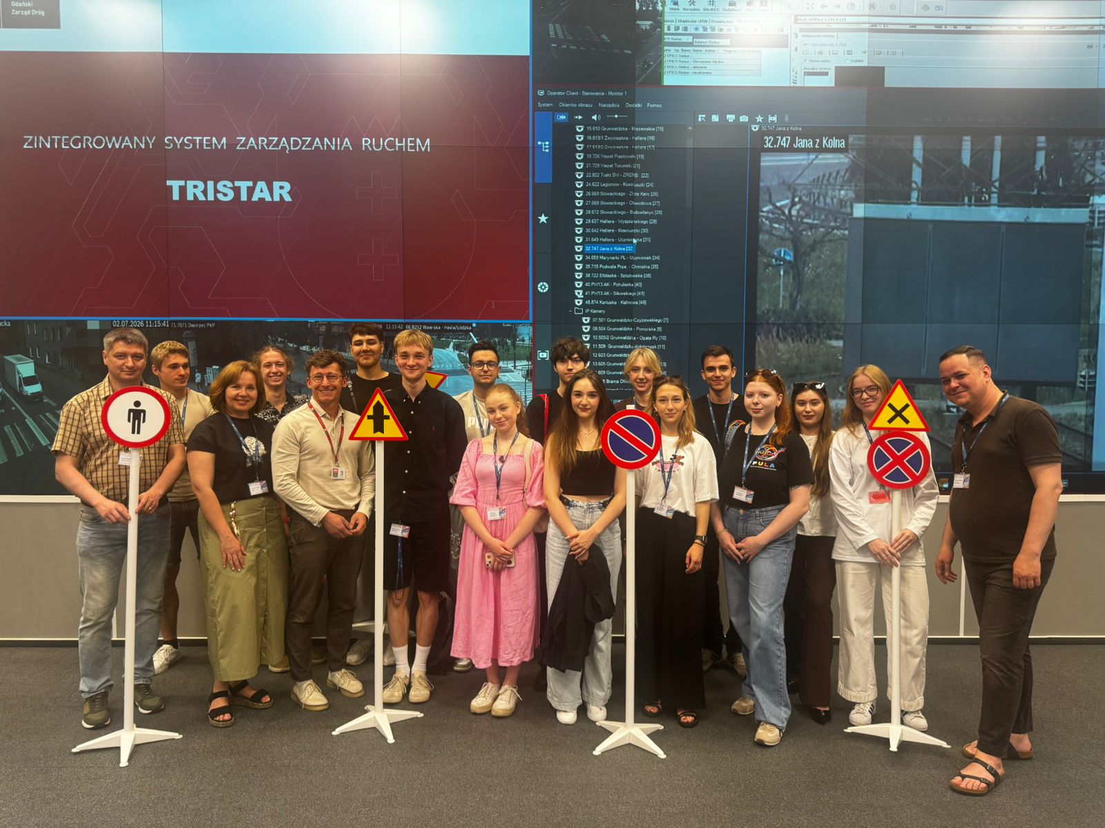 Photo of the PULA project participants at the Gdańsk Road and Green Areas Authority, against the background of a large-scale screen with panels monitoring traffic at Gdańsk intersections.